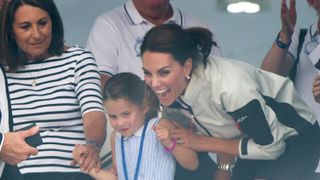 Carole Middleton and Catherine, Princess of Wales excitedly hold Princess Charlotte's hands as they attend the presentation following the King's Cup Regatta on August 08, 2019