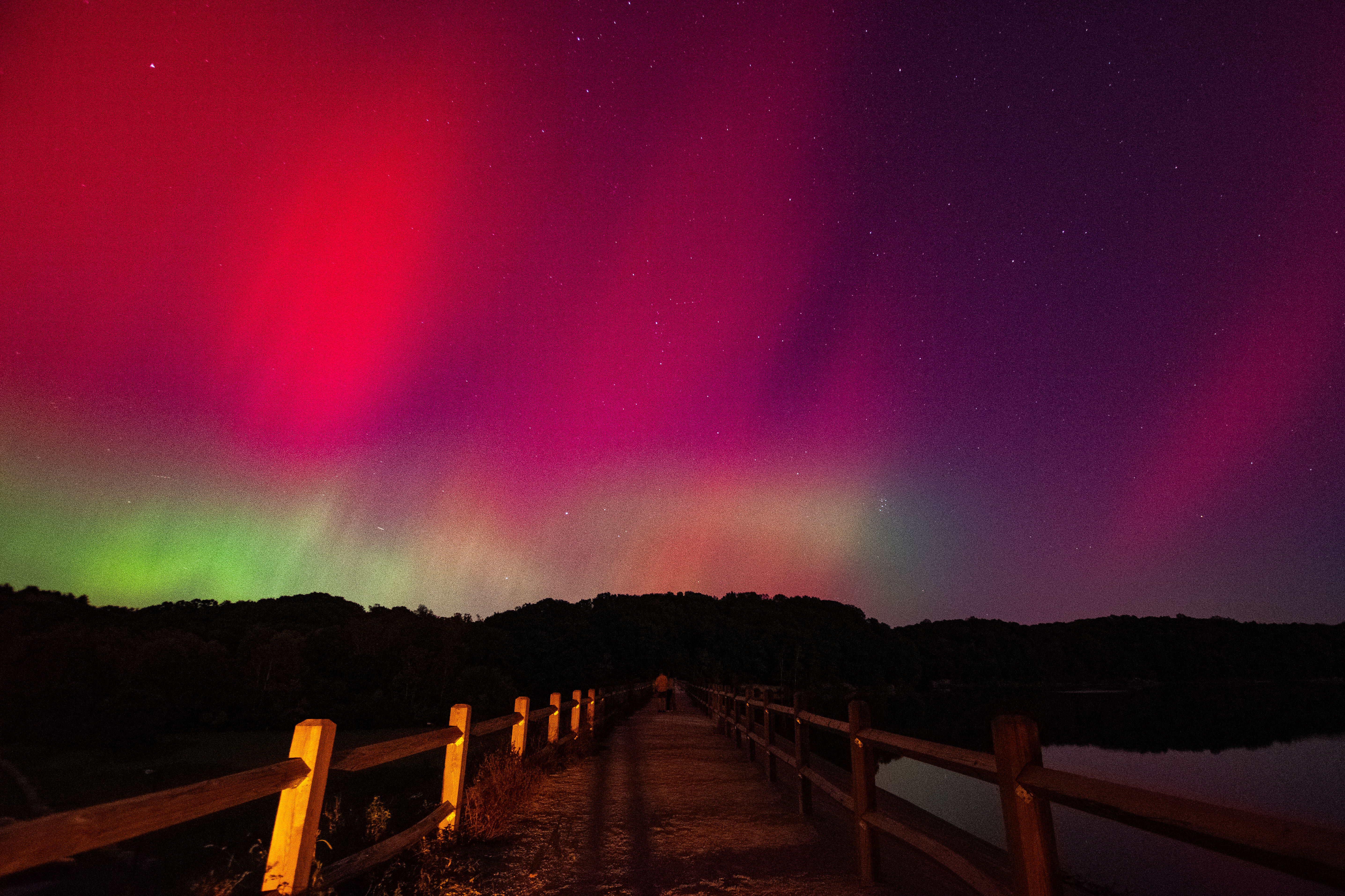 Green and pink lights over a brown wooden bridge