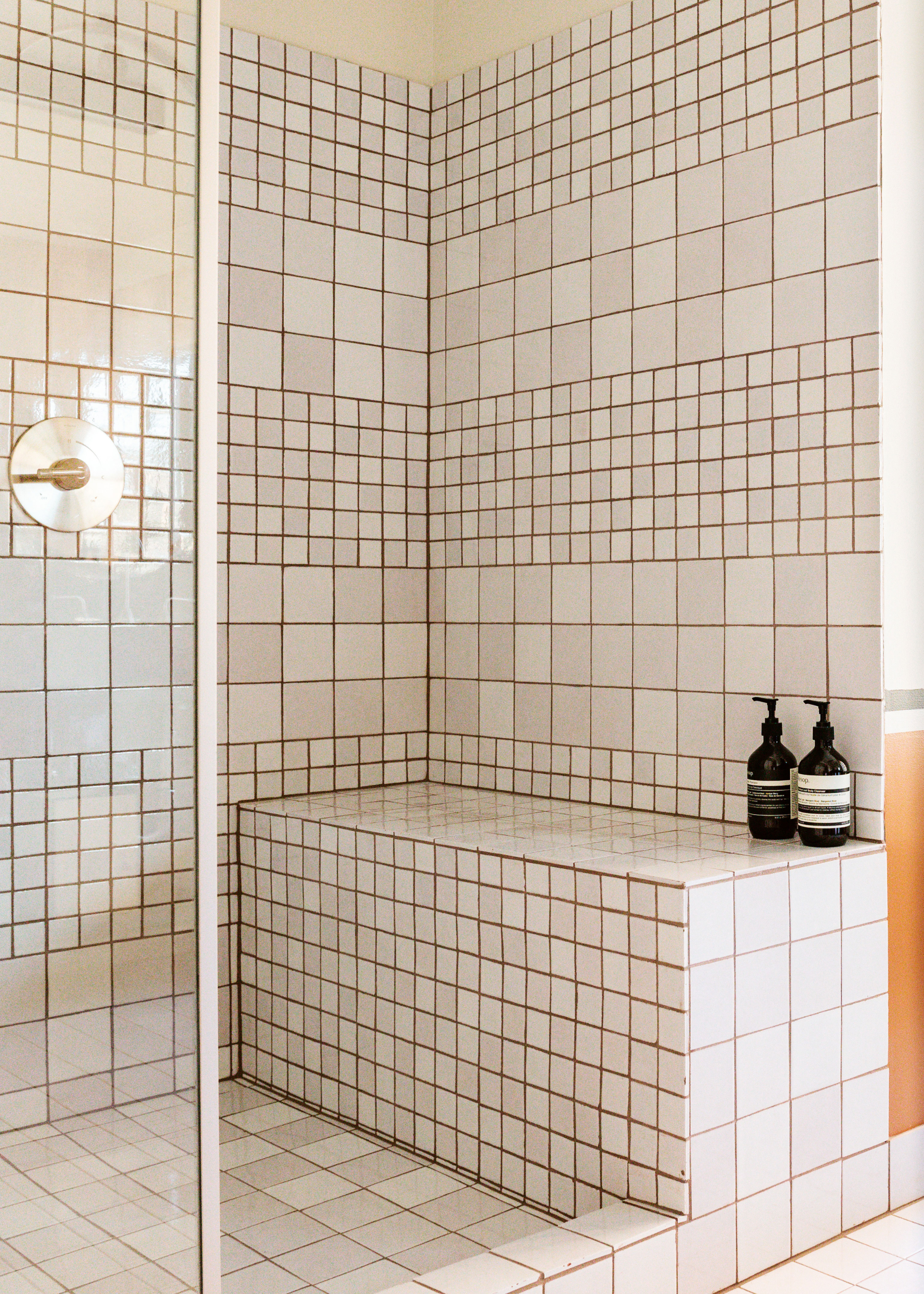 bathroom with small and large square tiles as well as a seating area that has a bath and body soap.