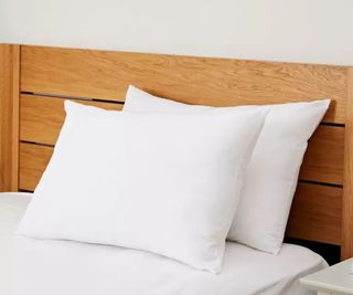 Two pillows stacked on top of each other on a bed with a wooden frame
