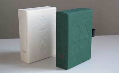 Two boxes of cards, one white and one green, with symbols embossed on the front