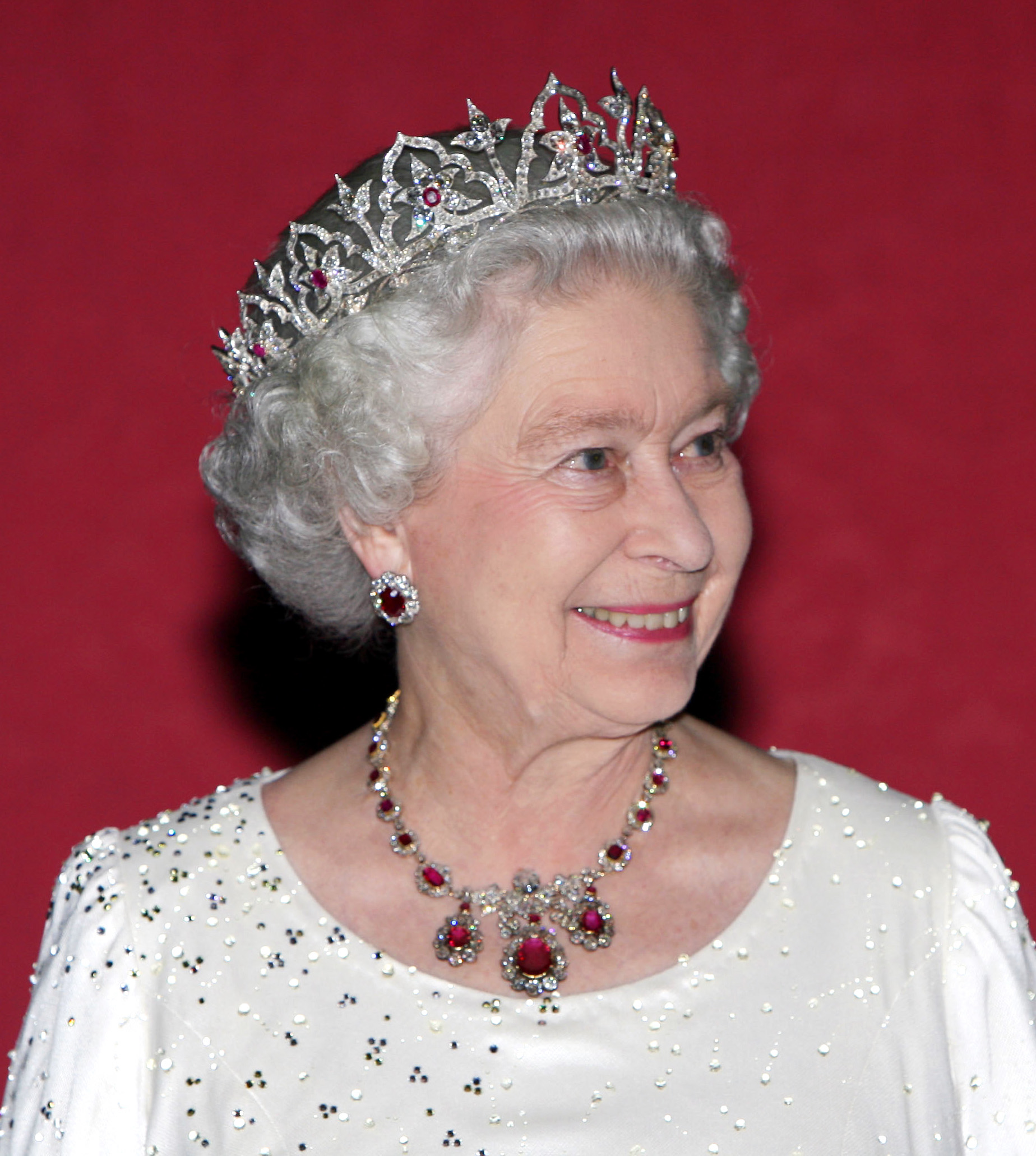 Queen Elizabeth wearing a white gown and tiara with a ruby necklace