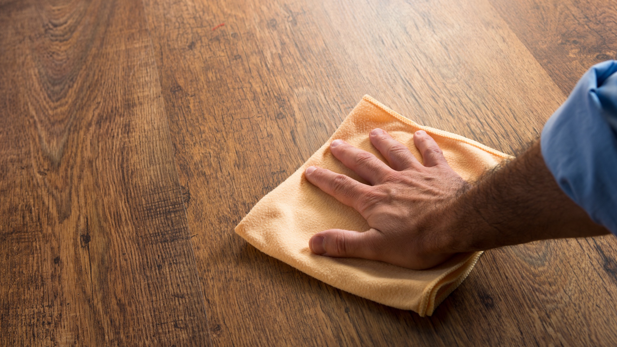 Man cleaning hardwood floor with cloth