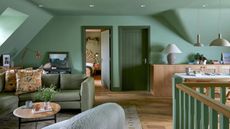 converted loft washed in green, with sofas, sideboard and view to bedroom