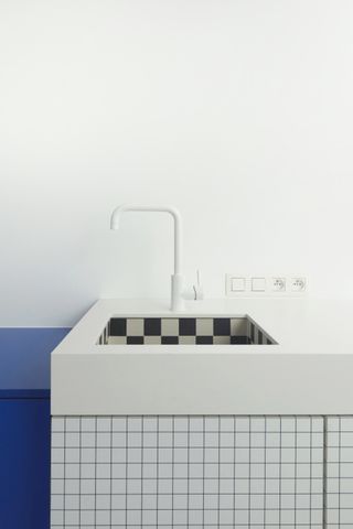 Minimal white kitchen sink with black and white checked tiles