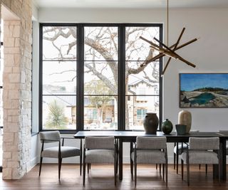dining room with gray upholstered chairs and big windows with sculptural contemporary pendant light