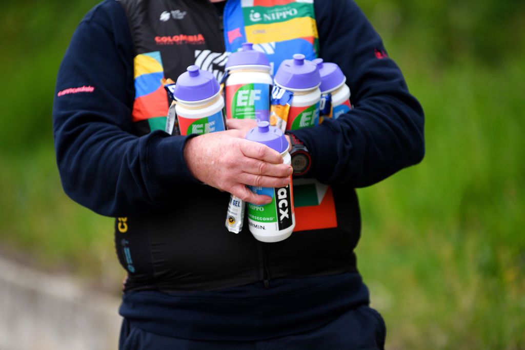 An EF Education-Nippo soigneur waits with bidons for riders in the Giro d&#039;Italia