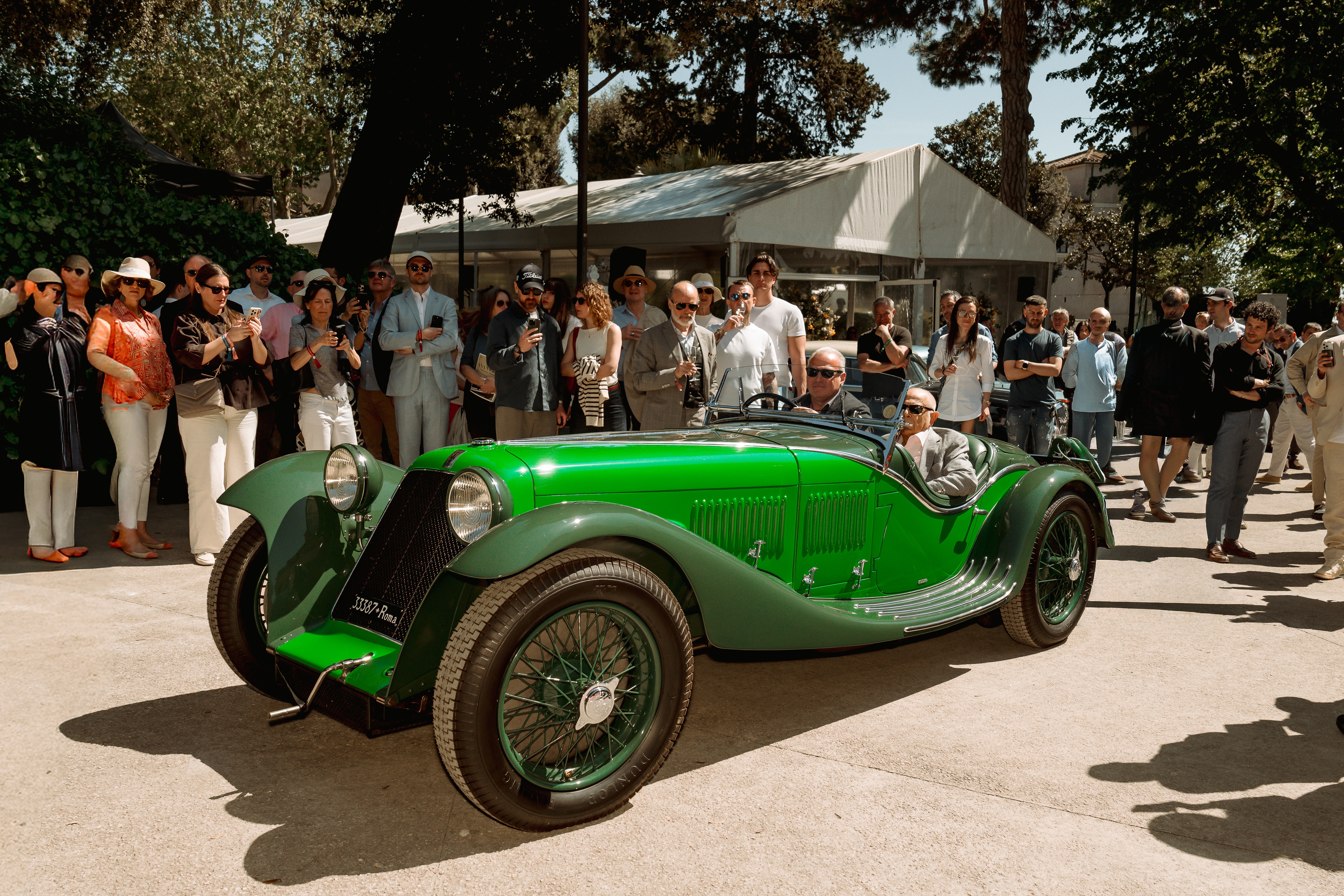 Bright green 1932 Maserati V4 Sport Zagato drives past spectators at Anantara Concorso Roma, with crowds gathered beneath trees to admire the award-winning pre-war sports car.