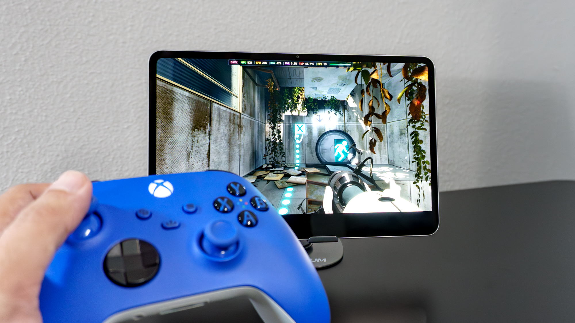 A person holding a controller in front of the RedMagic Astra 2 gaming tablet running the PC version of Portal 2 using emulation