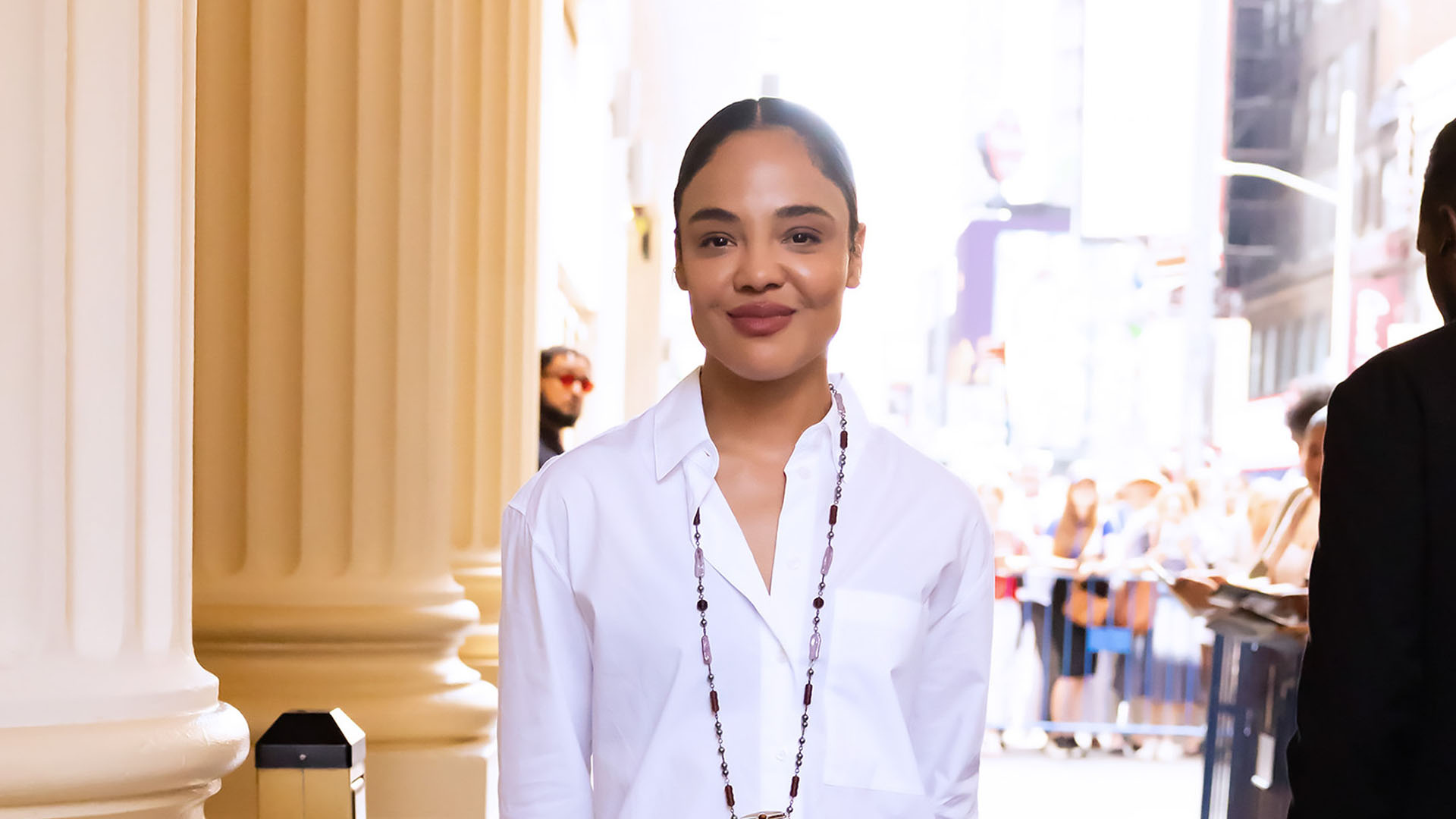 Tessa Thompson wearing a white button-dwon, black capri leggings, and purple mule heels