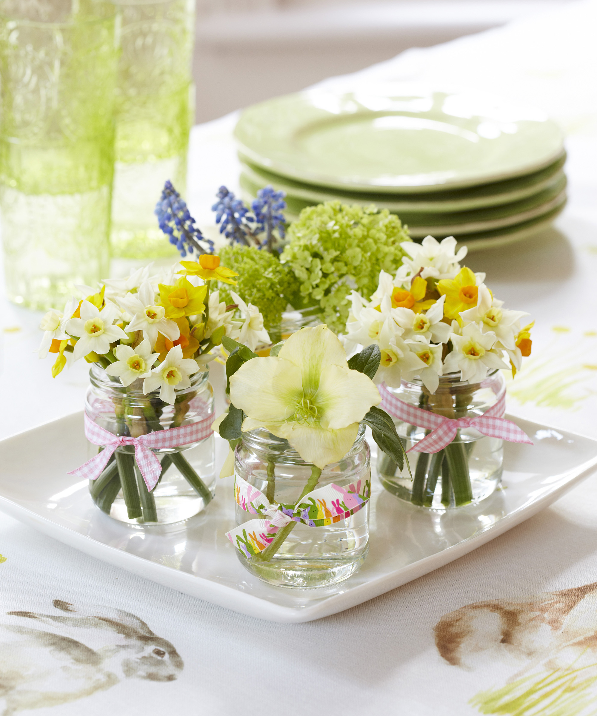 Easter table centerpiece using jars filled with spring flowers and tied with ribbon