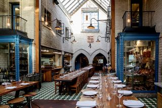 A church-like building houses a restaurant filled with wooden tables and brasseries-inspired decor.