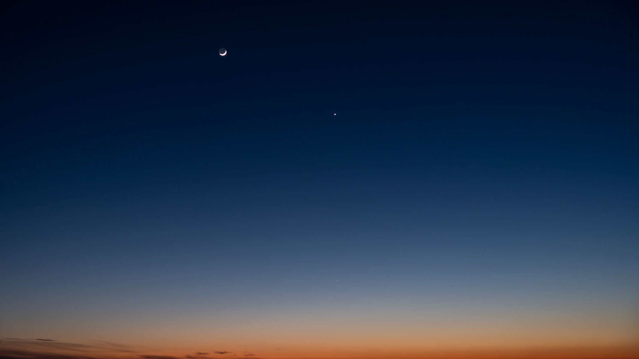 A crescent moon with Venus in a sunset sky
