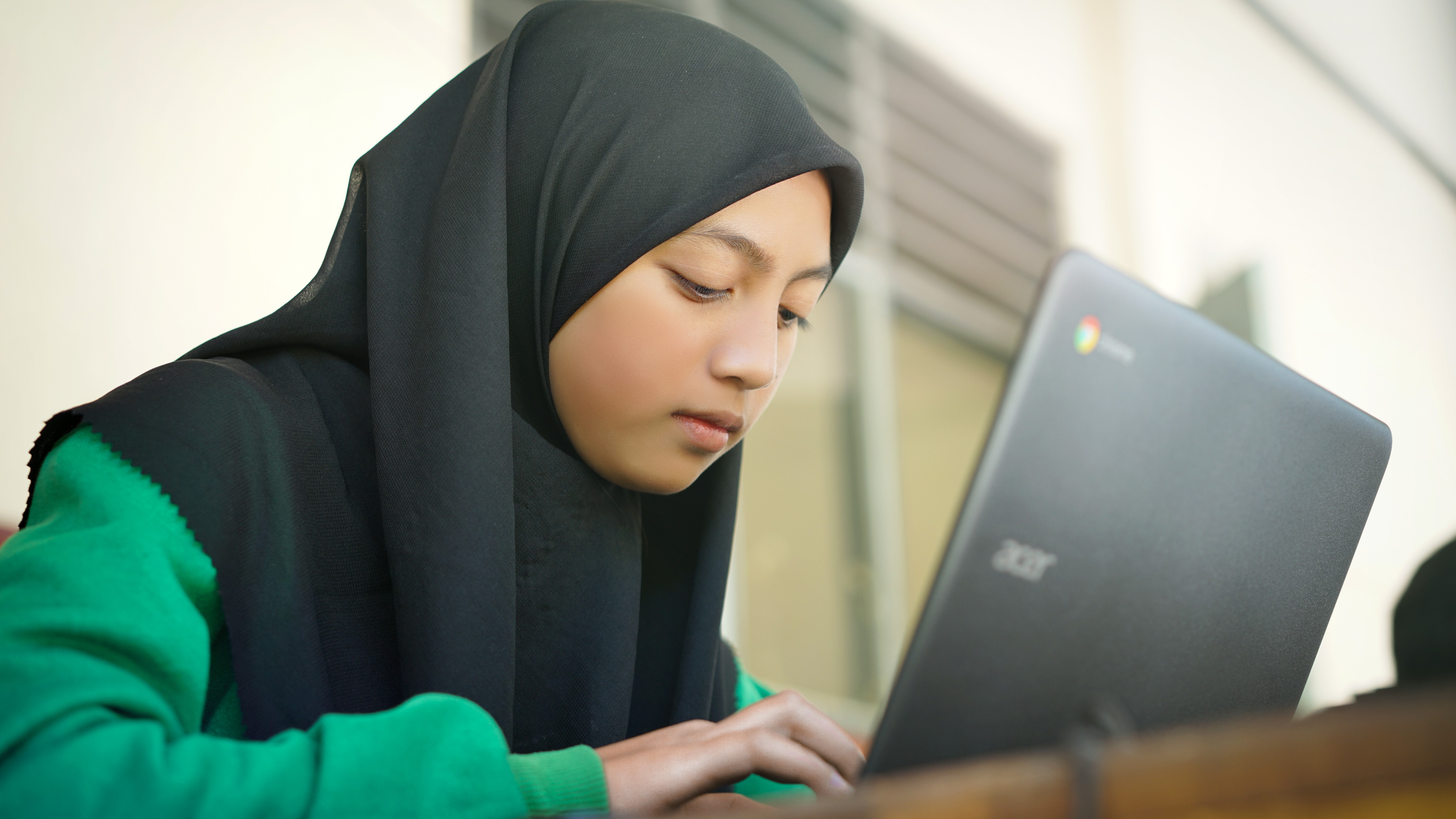 A younger student possibly studying remotely using a Chromebook laptop