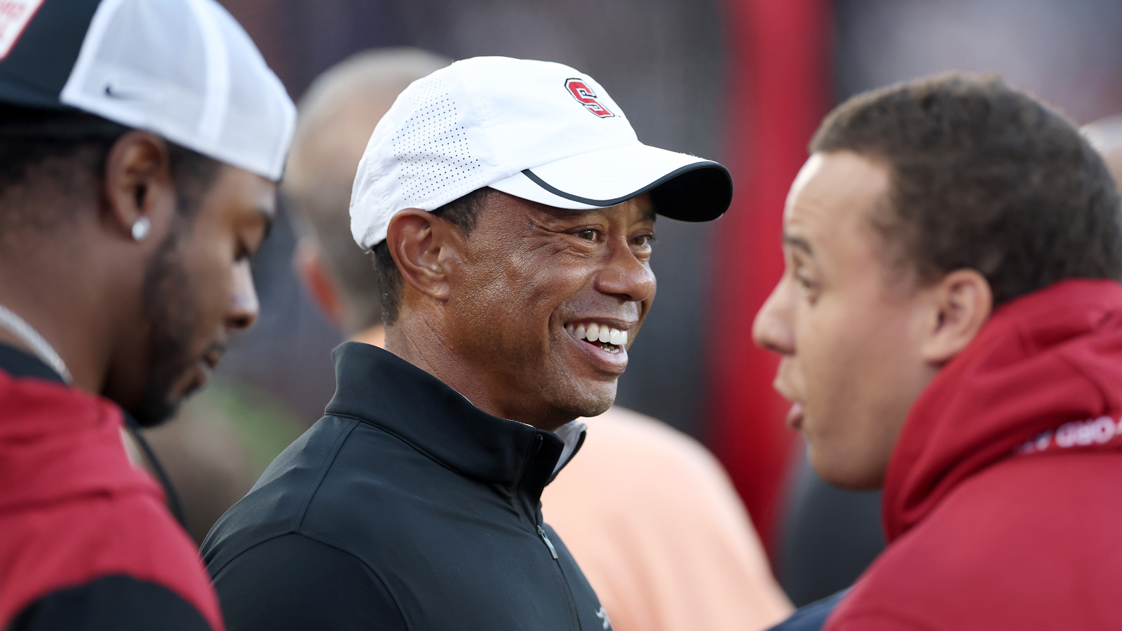 Tiger Woods smiles while looking on at an American Football match