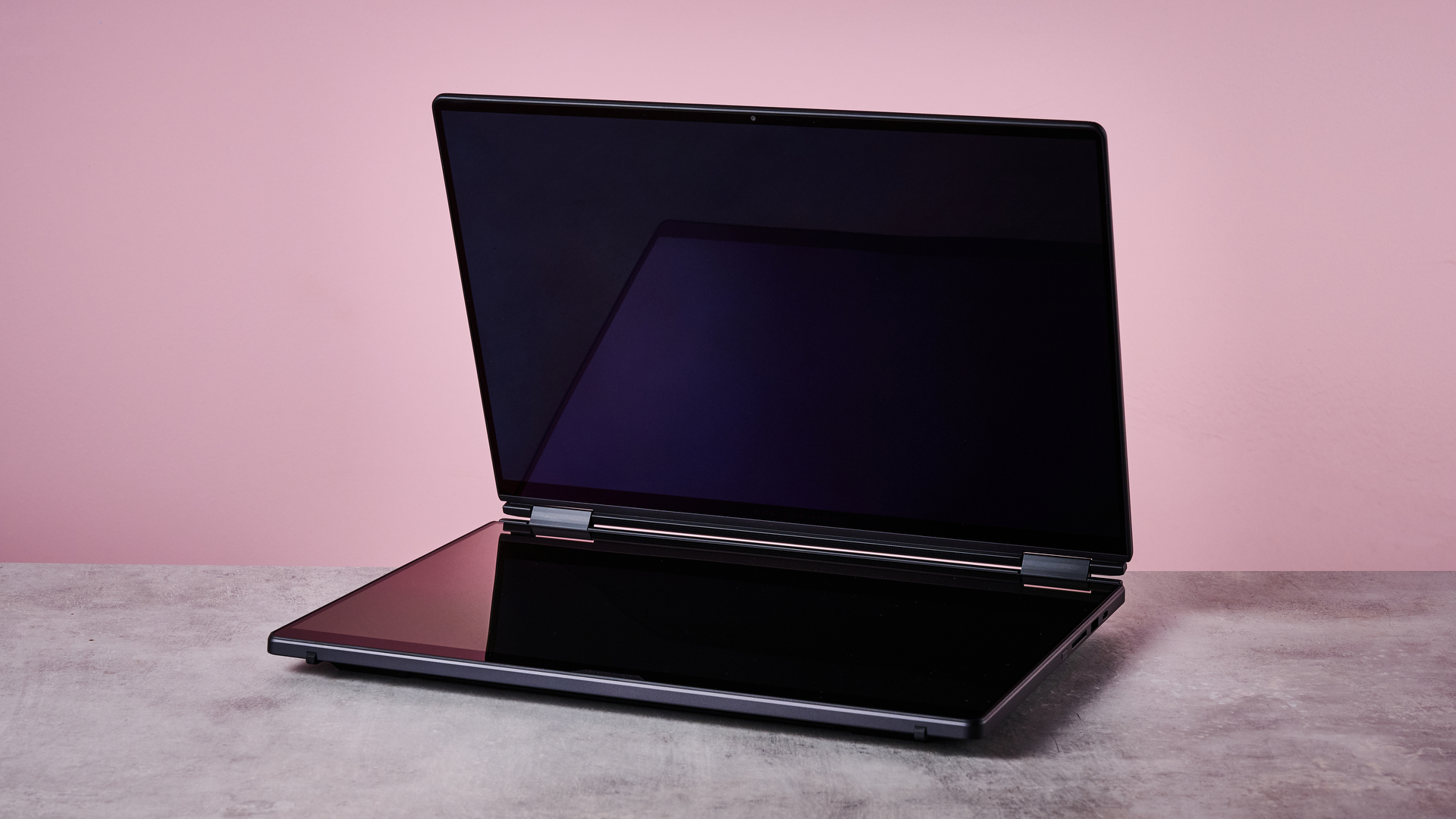Three-quarter view of ASUS ROG Zephyrus Duo 2026 on a desk with pink wall in background