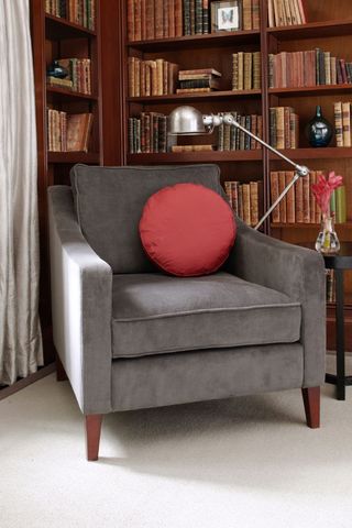 grey armchair with pink circular pillow with bookshelves