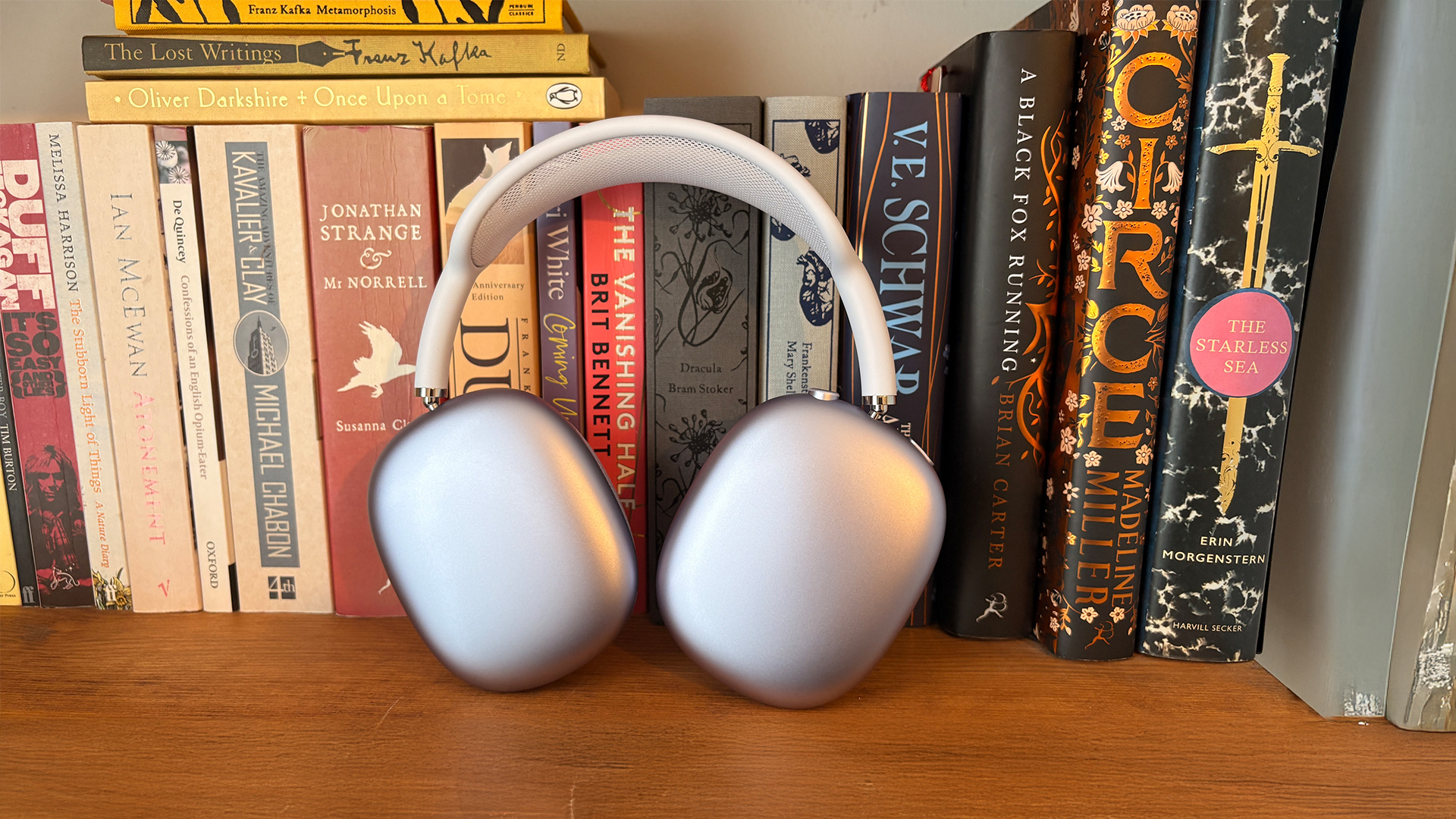 Apple AirPods Max 2 over-ear headphones leaning against books on bookshelf