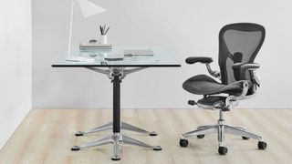 A Herman Miller Aeron chair in front of a glass desk