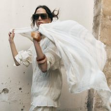 Zara model wearing a white blouse with a matching scarf and oversize sunglasses