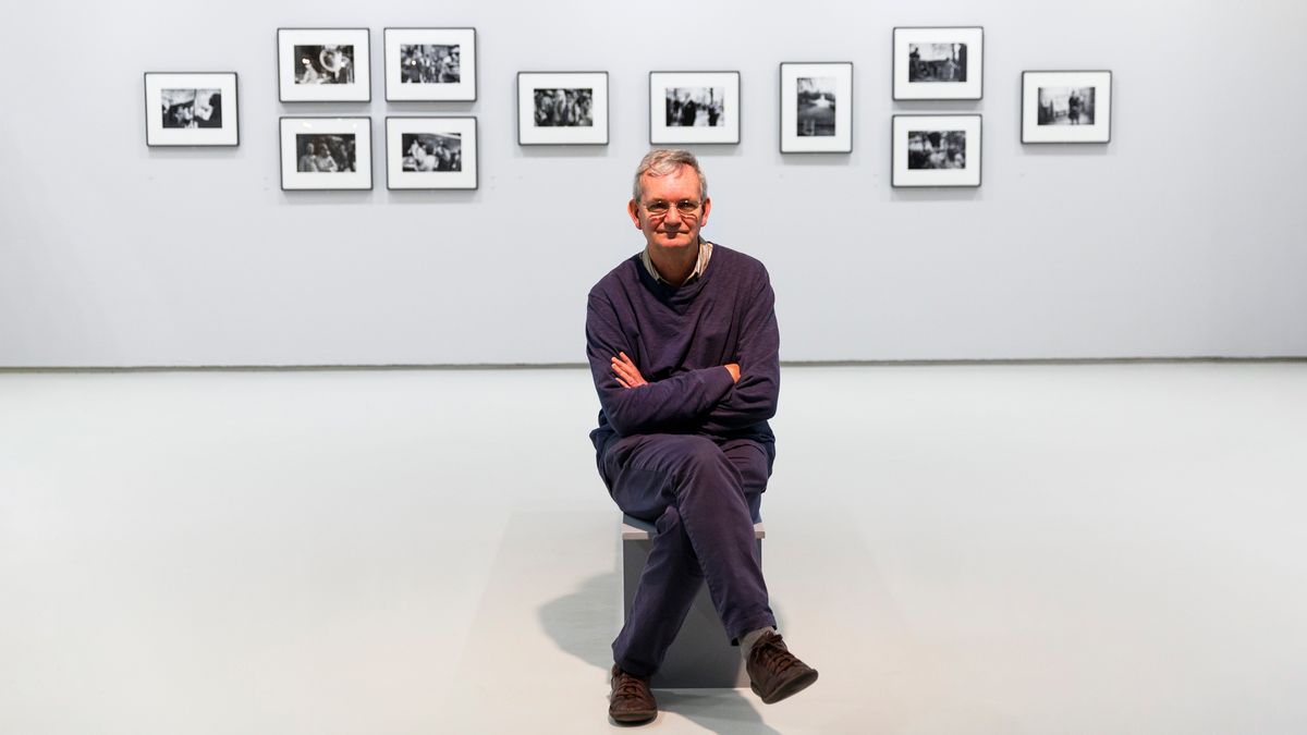 Martin Parr sits in front of photo exhibition