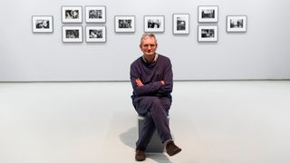 Martin Parr sits in front of photo exhibition