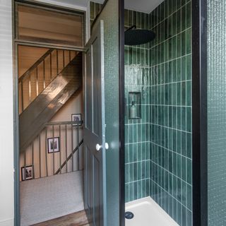 Teal-tiled shower cubicle and landing with dark-painted staircase