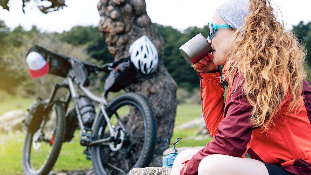 bikepacker drinking a mug of hot drink