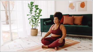 Body positive woman doing mindfulness workout at home. Beautiful female in sports wear practicing meditation at home.