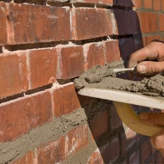 Person repointing the outside of a brick house