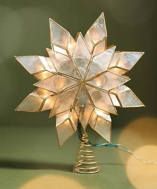 A star-shaped Christmas tree topper made from mollusc shell and brass metal coil with built-in LED light