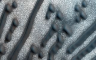 A new NASA image of dark dunes on the Martian surface bears a striking resemblance to the dots and dashes of Morse code.