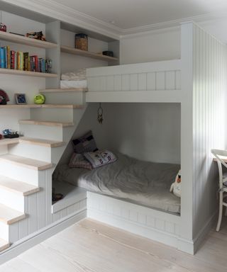 A gray painted loft bed with a full staircase and bottom bunk