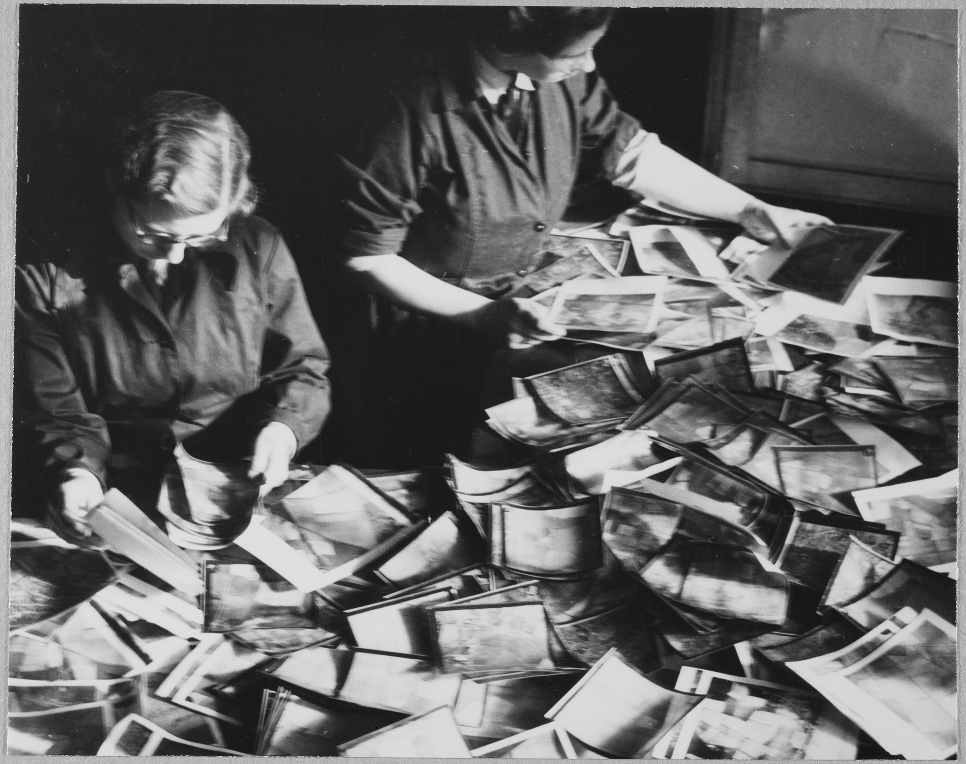 Two Women's Auxiliary Air Force (WAAF) trainees sorting through piles of aerial photographic prints during training at the No.2 School of Photography in Blackpool