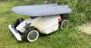 robot mower in charging garage on lawn