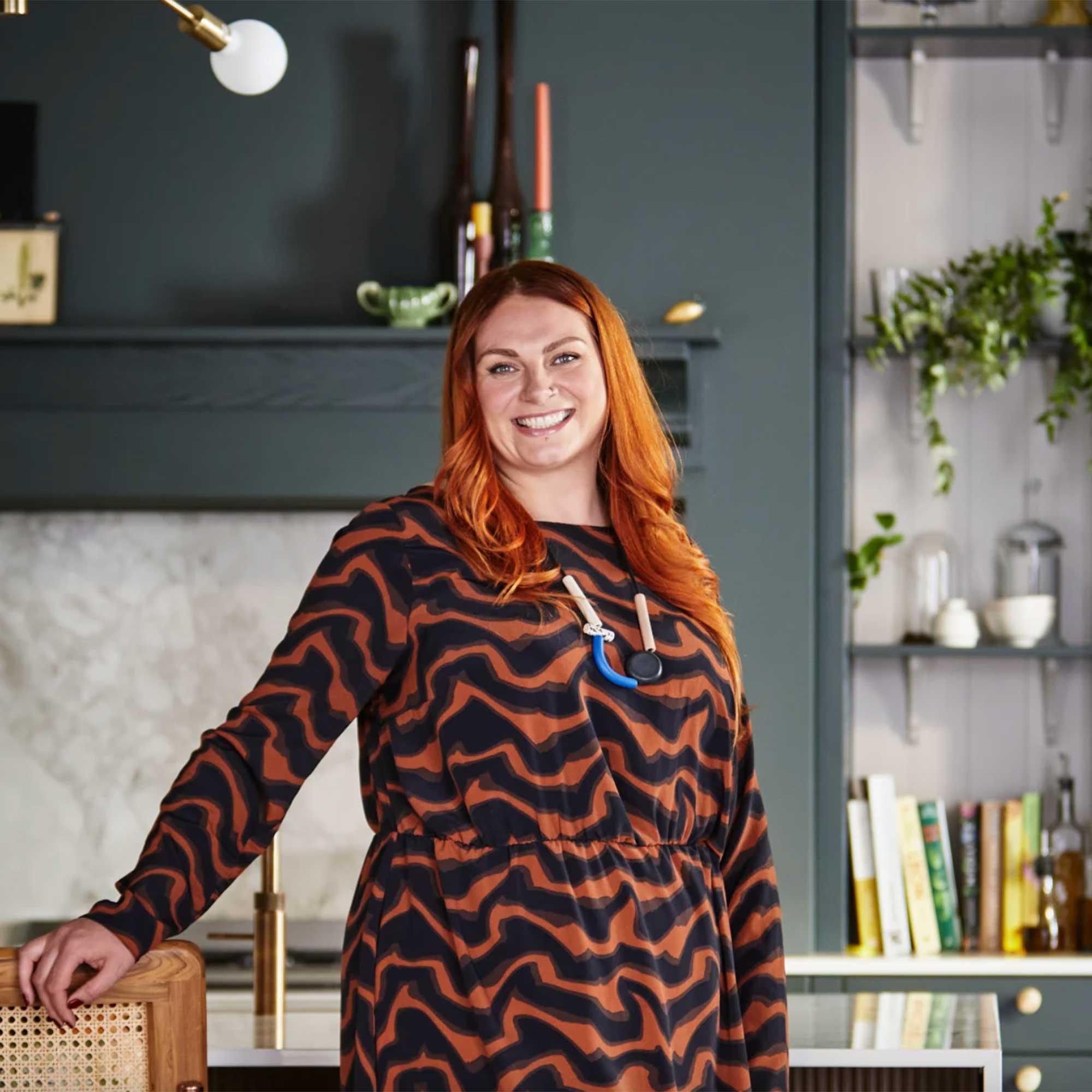 Magnet kitchen designer Jen Nash  standing in a dark green kitchen