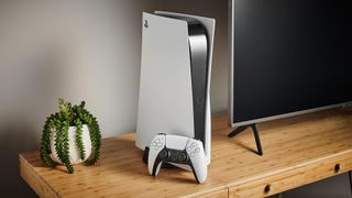 En PlayStation 5 står uppställd tillsammans med sin kontroller bredvid en TV på en TV-bänk.