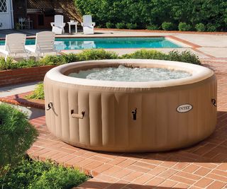 inflatable hot tub on a patio next to a pool