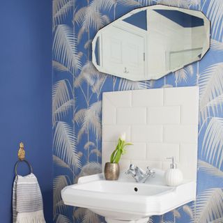 bathroom wash basin with palm fronted wallpaper and mirror