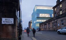 Photograph captured from the corner of hill street with blurred image of 2 people walking on the street and on the right 3 buildings with the Reid building in the center.