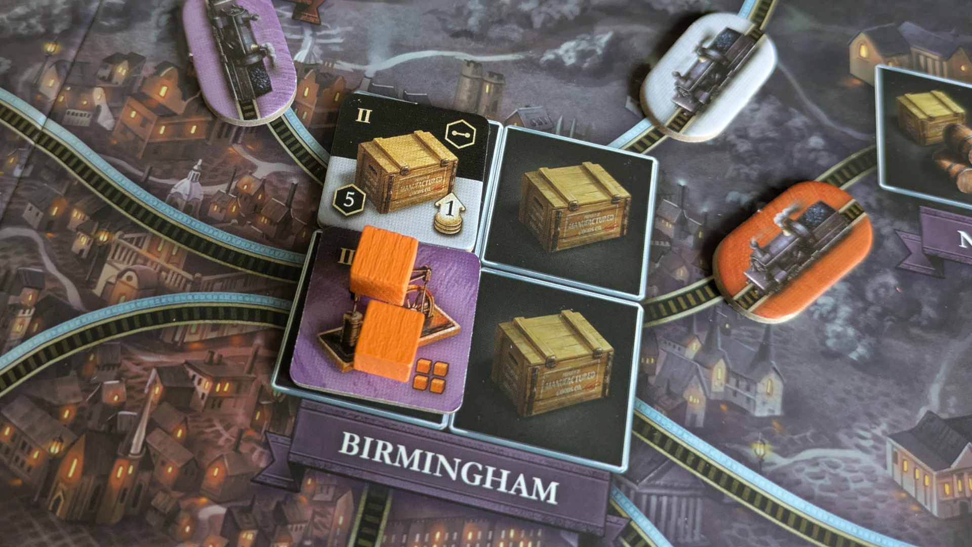 Orange cubes, crate tokens, and train tokens surrounding the Birmingham place setting on the Brass: Birmingham board