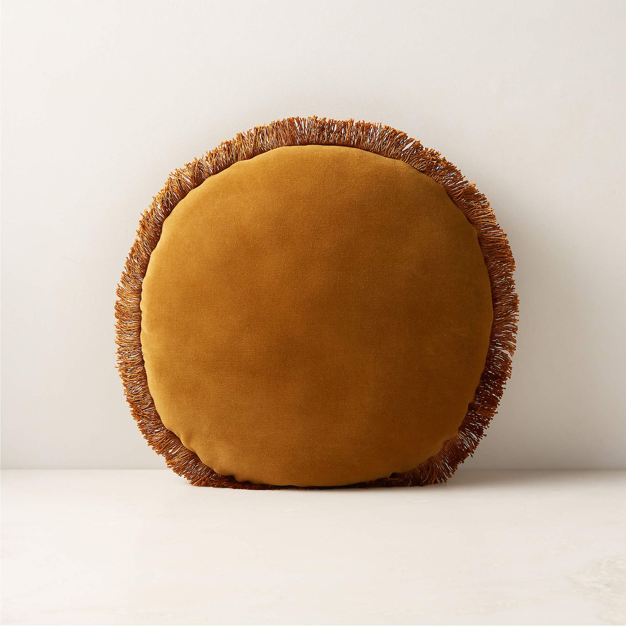 Round mustard velvet cushion with fringe trim