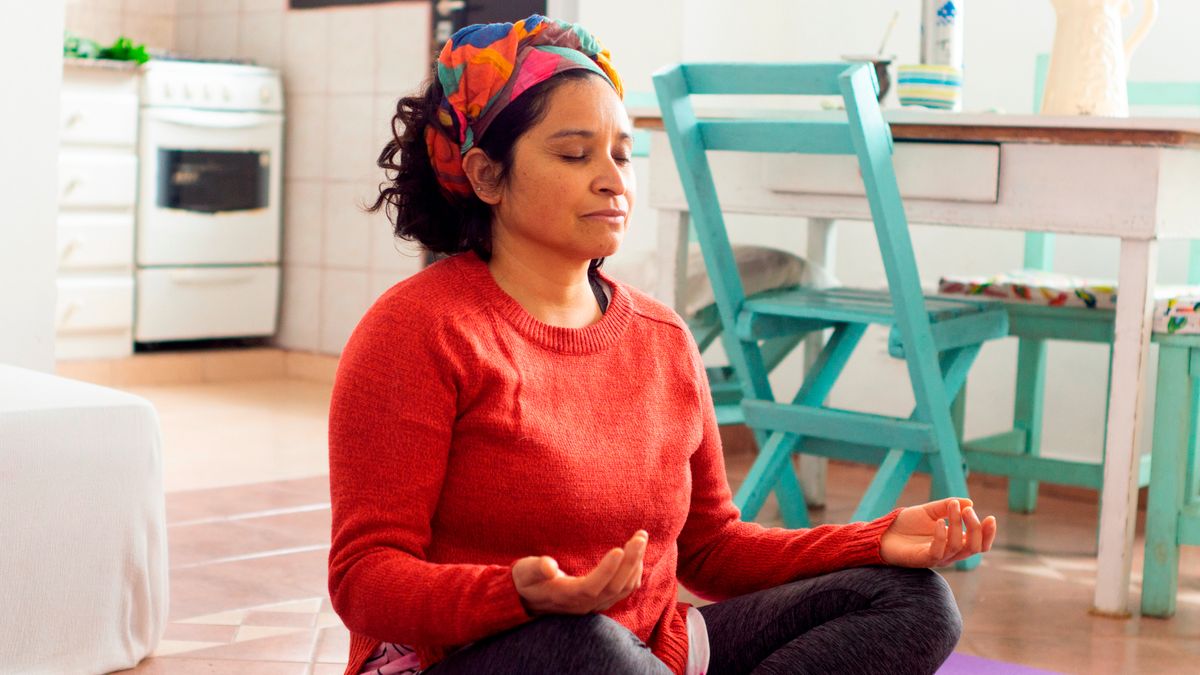 Woman sitting cross-legged on floor with hands resting on knees, palms raised