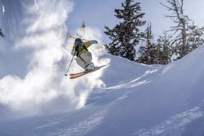 A person on skis flies over a jump surrounded by snow.