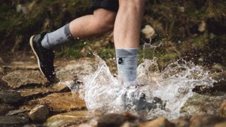 Man running through stream weaing SealSkinz waterproof socks
