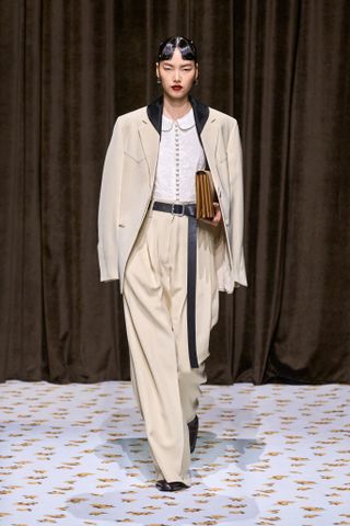 a model wears a beige suit on the runway at Jil Sander