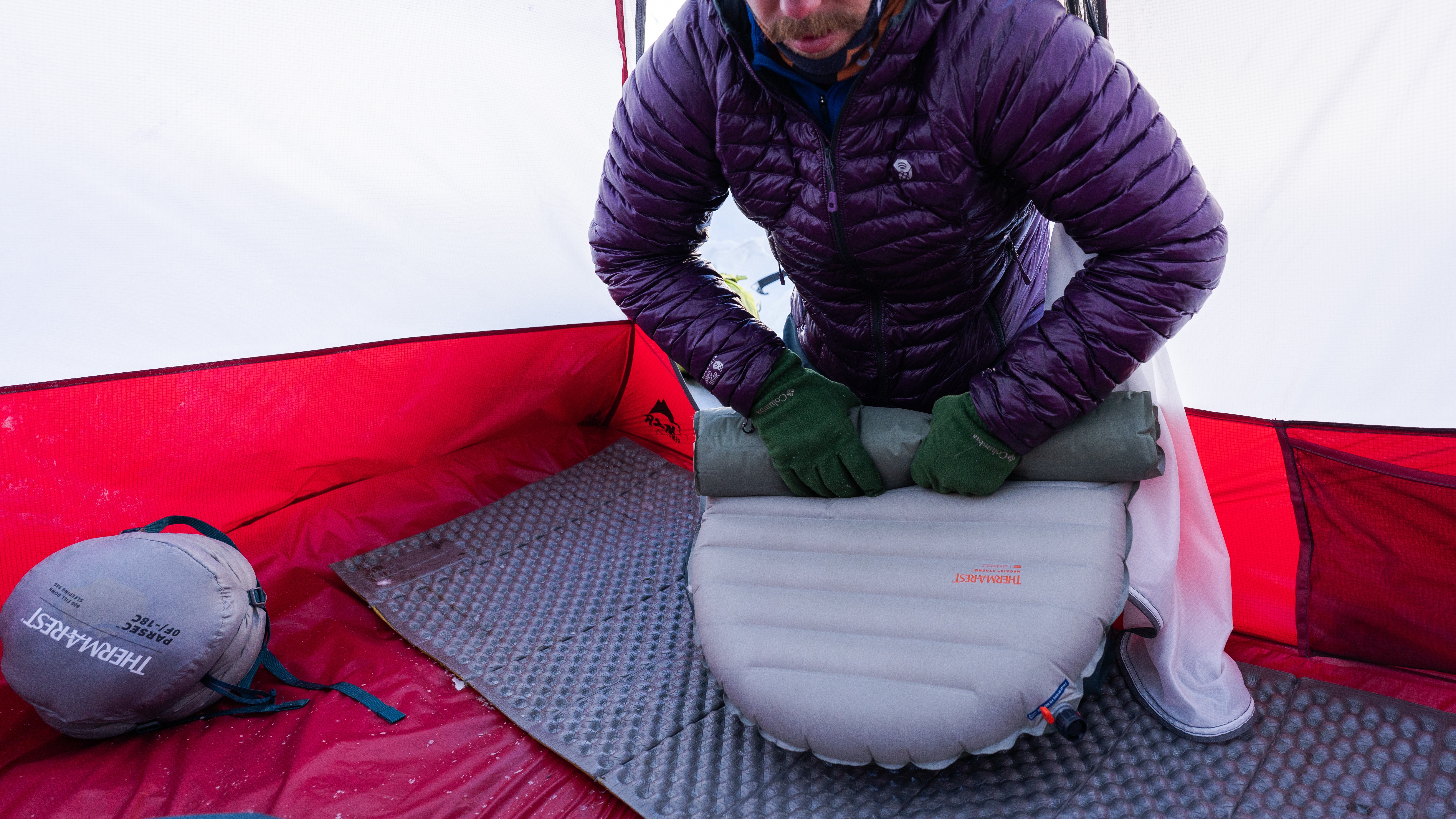 Cold camper rolling up his sleeping pad while kneeling on the Therm-a-Rest Z Lite Sol sleeping pad