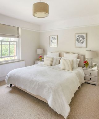 Beige bedroom with queen size bed and grey side tables with grey lamps on