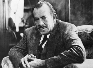 John Steinbeck looks on whilst sat in a chair