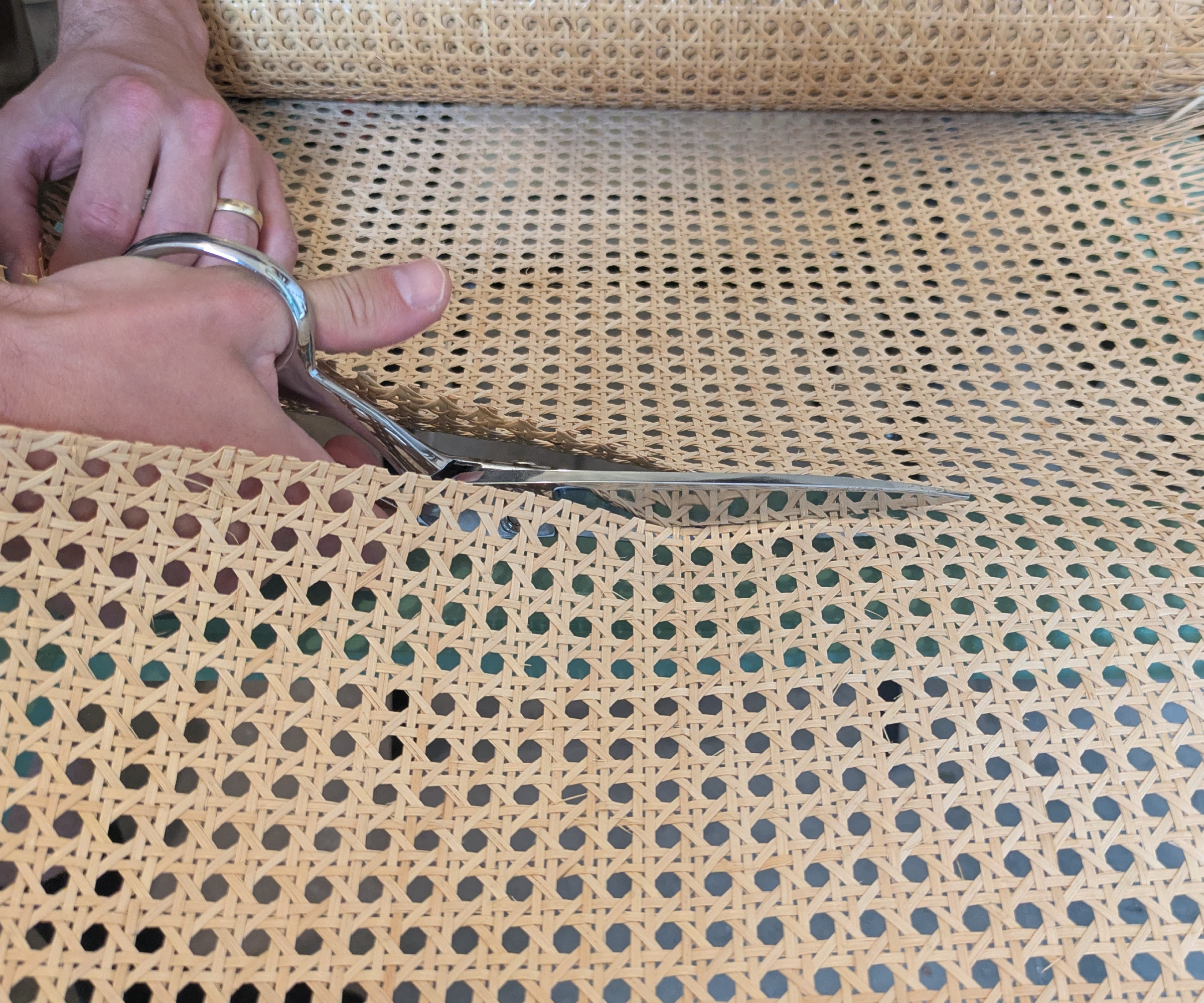 Scissors cutting through cane webbing